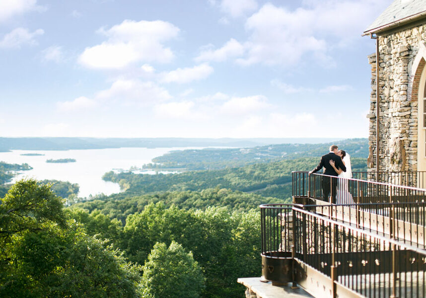 Top of the Rock chapel wedding venue at Big Cedar Lodge Bride and groom kissing on the balcony of a Big Cedar Top of the Rock chapel with Table Rock Lake in the distance.