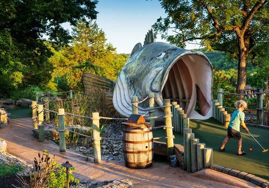 A young boy playing on the Big Bass Mini Golf course