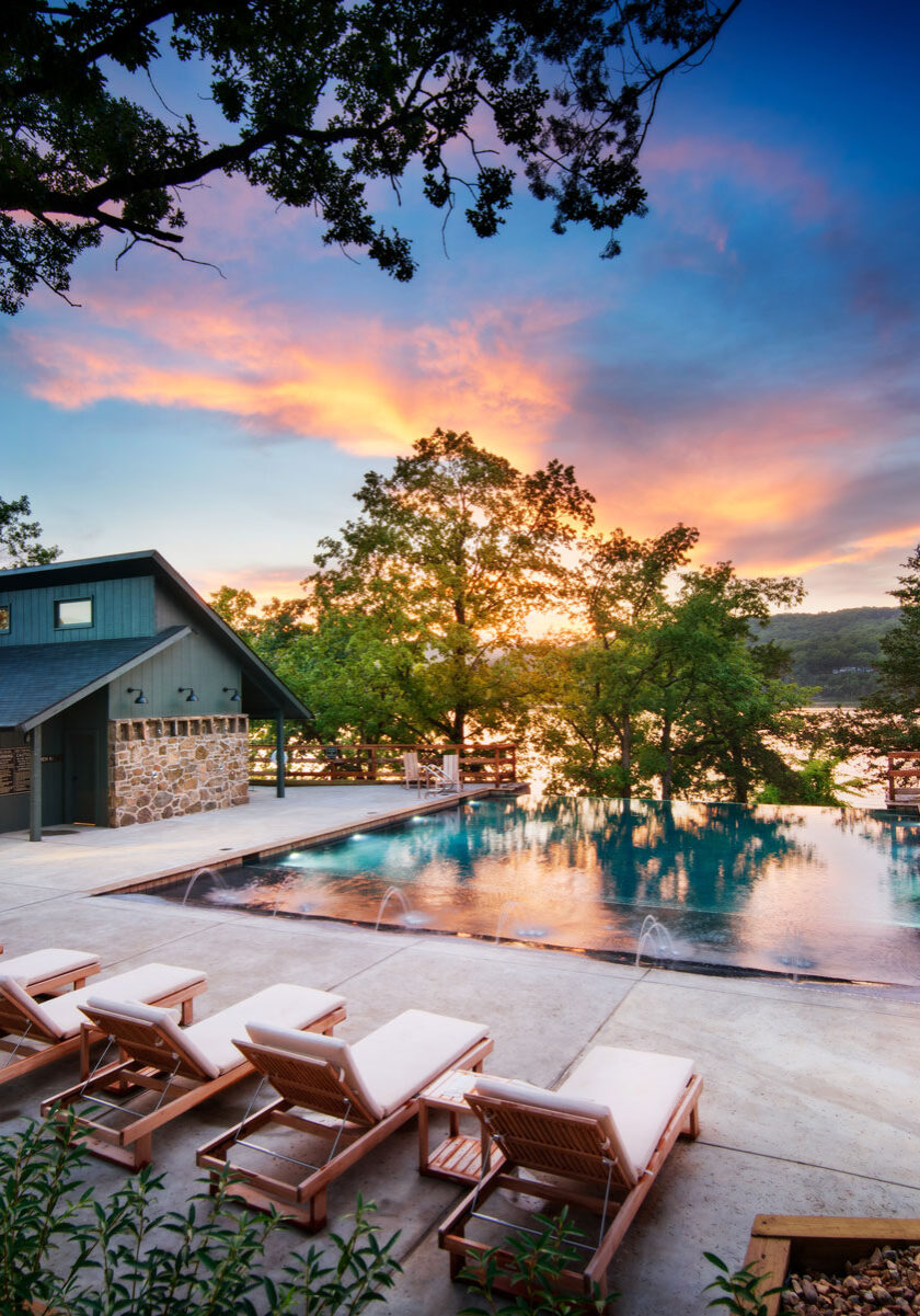 Camp-Long-Creek-Pool Camp Long Creek swimming pool lined with reclining chairs, vivid sunset and lake in the background