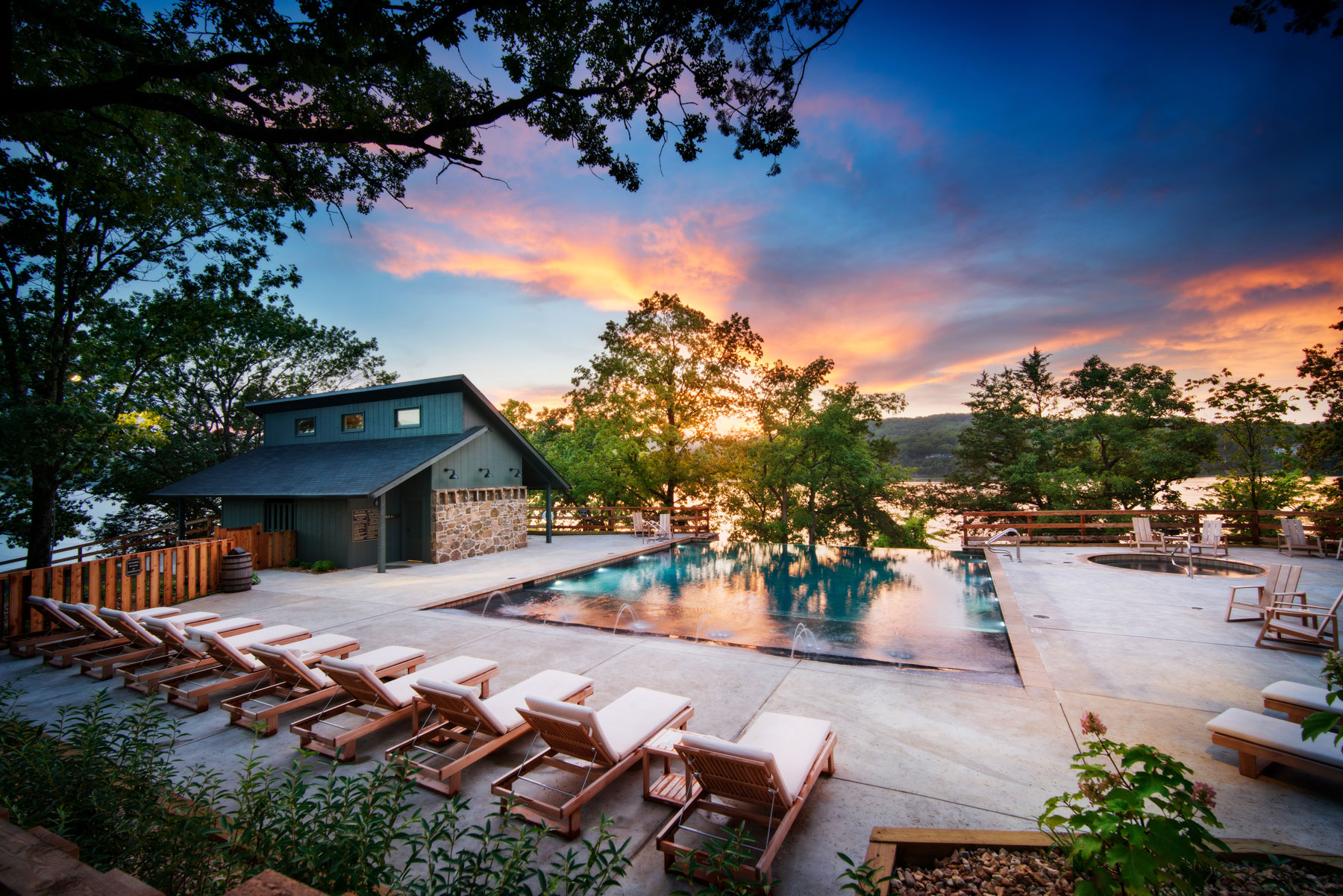 Camp-Long-Creek-Pool Camp Long Creek swimming pool lined with reclining chairs, vivid sunset and lake in the background