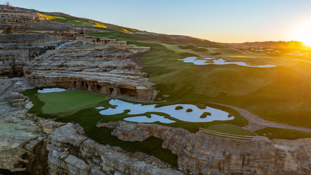 The sun sets over a mountain ridge at Cliffhangers golf course at Big Cedar Lodge