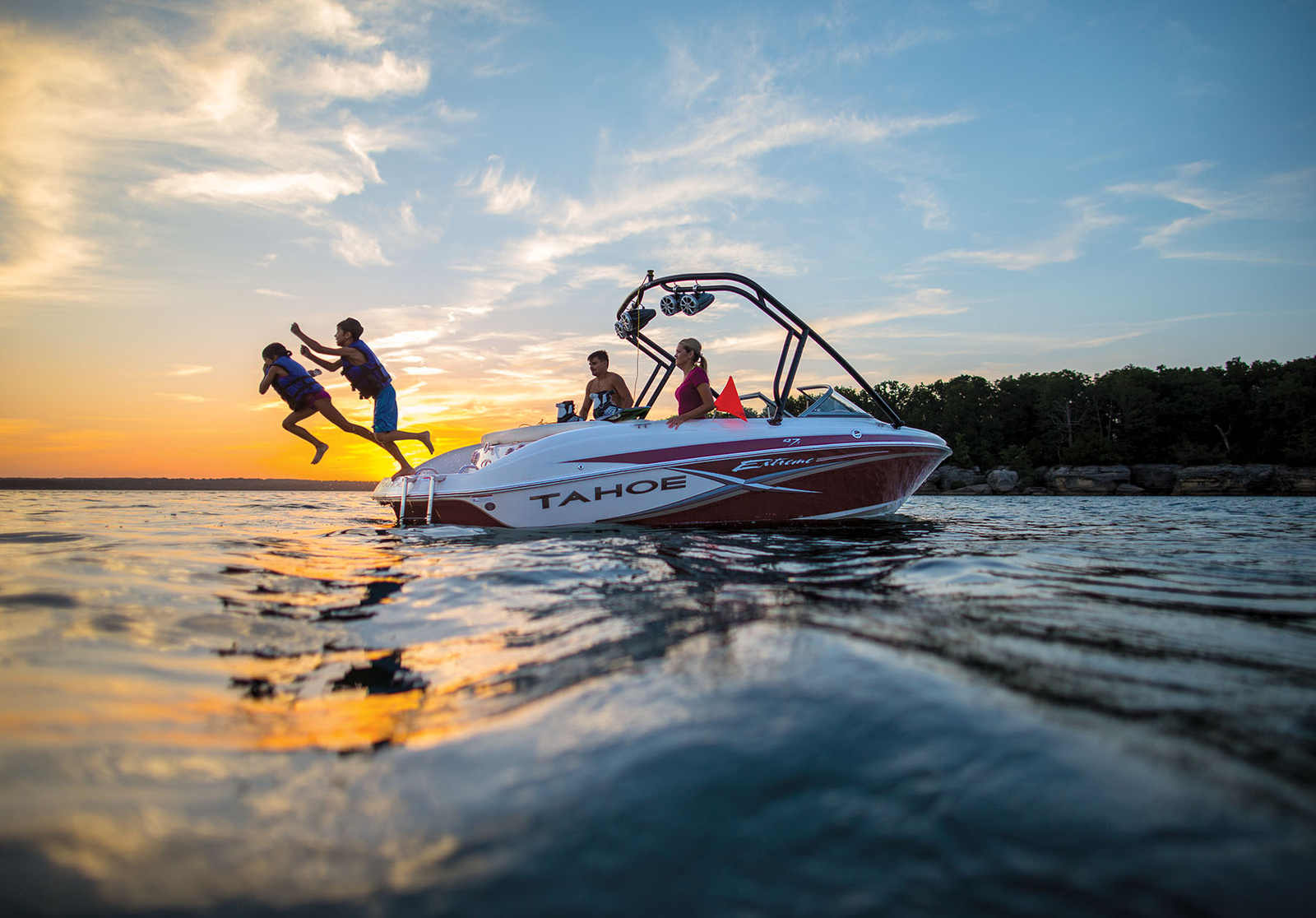 children jump off the back of a boat during sunset on table rock lake