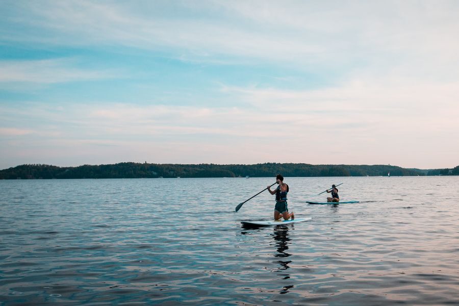 Stand-up Paddleboarding two individuals paddleboarding on a lake.
