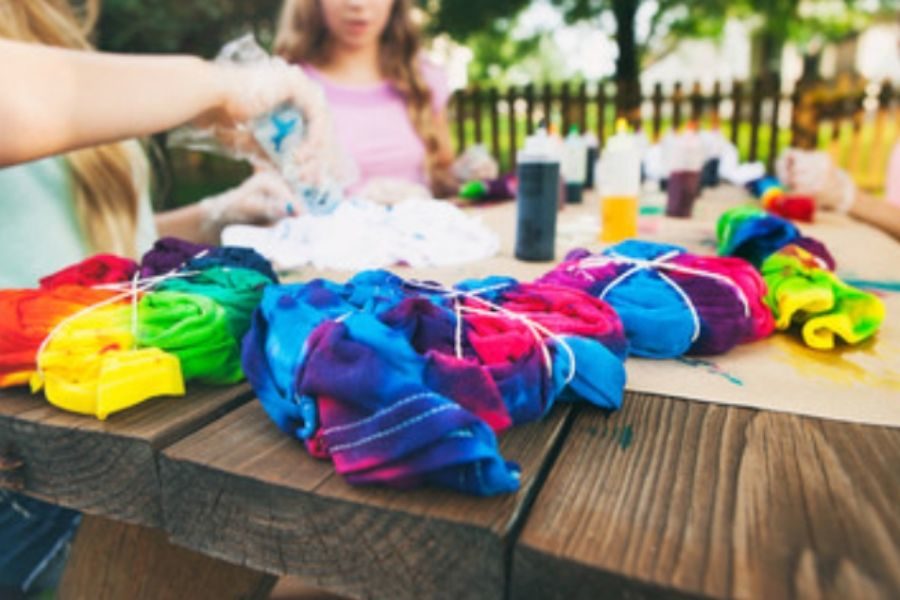 Tie Dye Children tie dying t-shirts on rustic wooden table