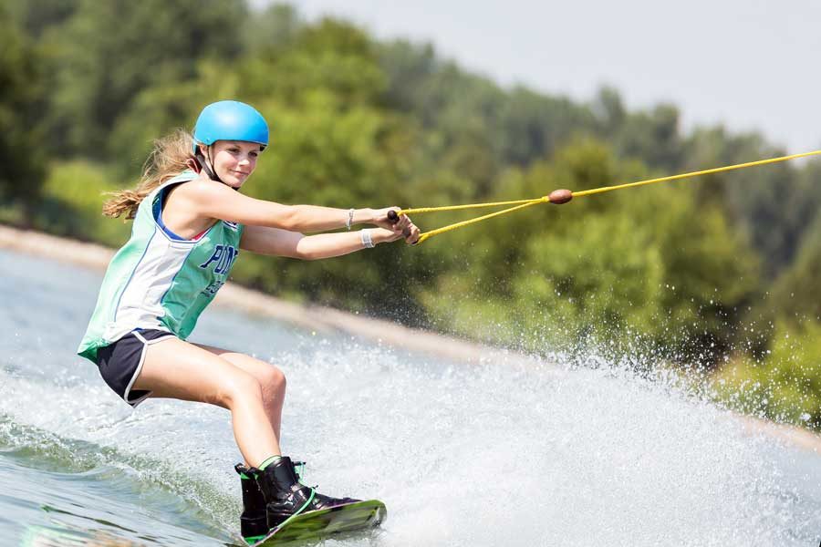 Wakeboarder-web Woman wakeboarding on the lake with thick foliage in the background